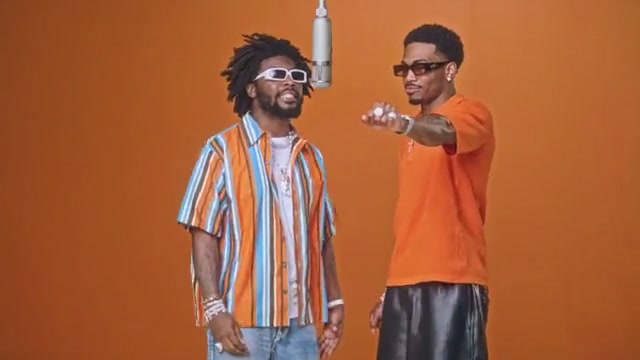 Two friends in sunglasses perform together in the orange Hotel Lobby studio