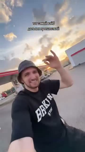 Source selfie of the camera operator in a dark shirt and bucket hat, caption still visible