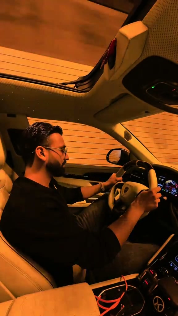 Passenger-seat view of a driver under amber tunnel lights, with a camera sweep across the dashboard and back