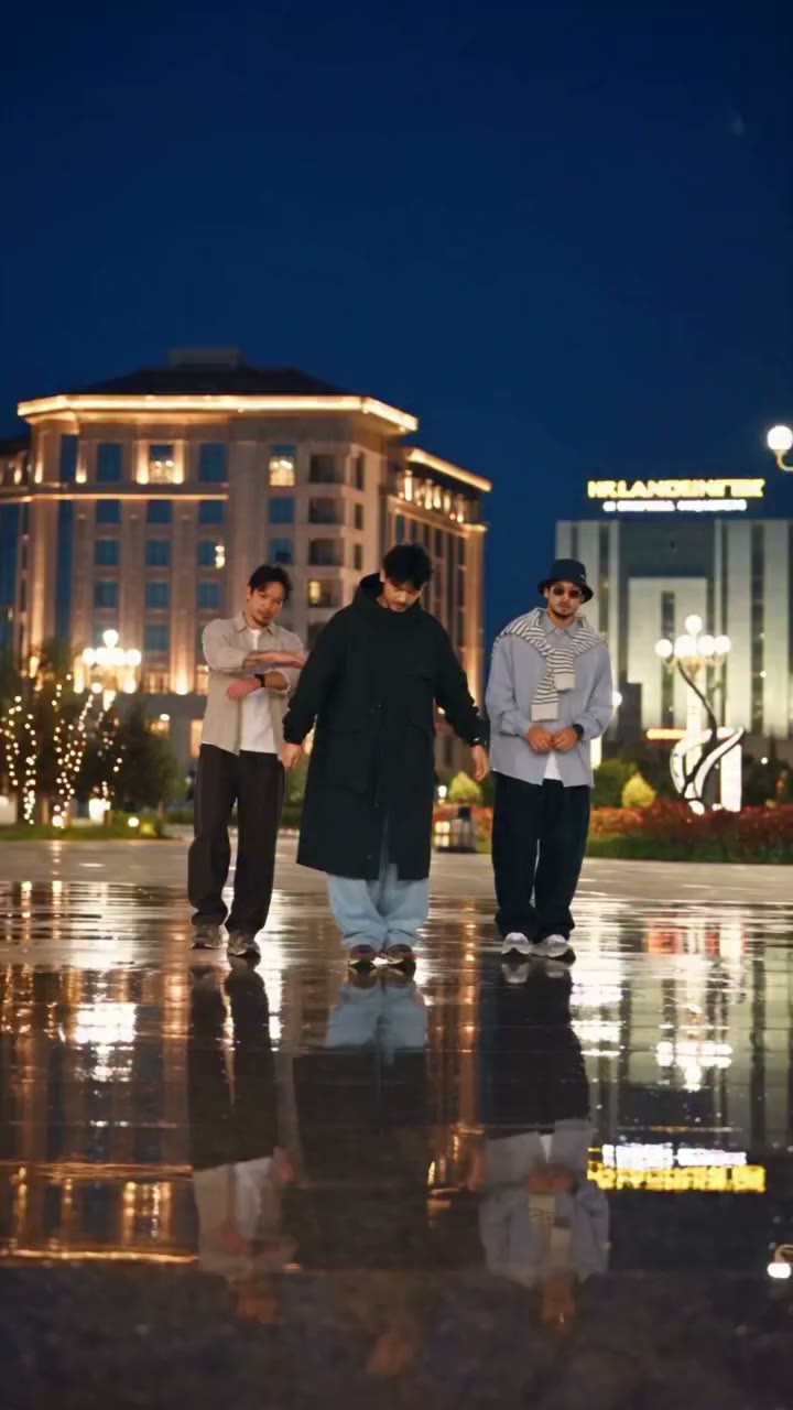 Original three-person shuffle on a wet nighttime plaza, with a center-front dancer and one performer on each side