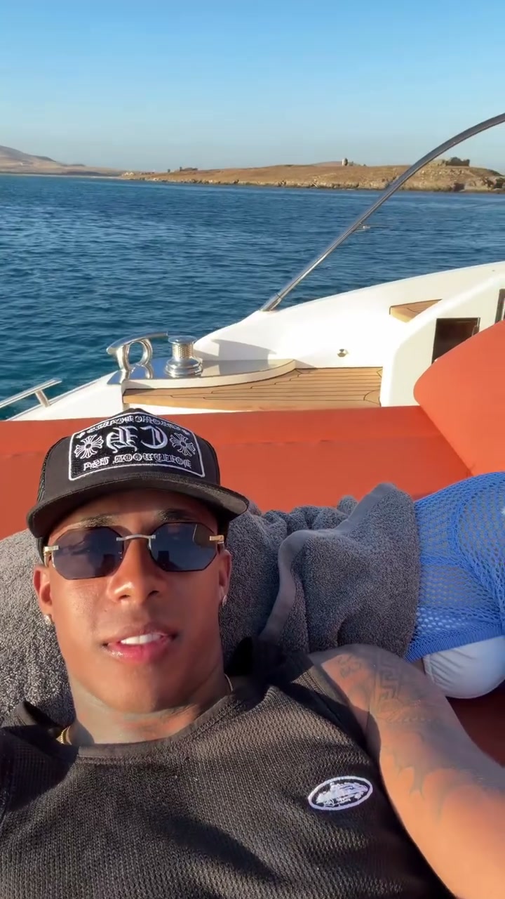 Two people relaxing on orange yacht cushions while a selfie camera pans across the sunset sea and back